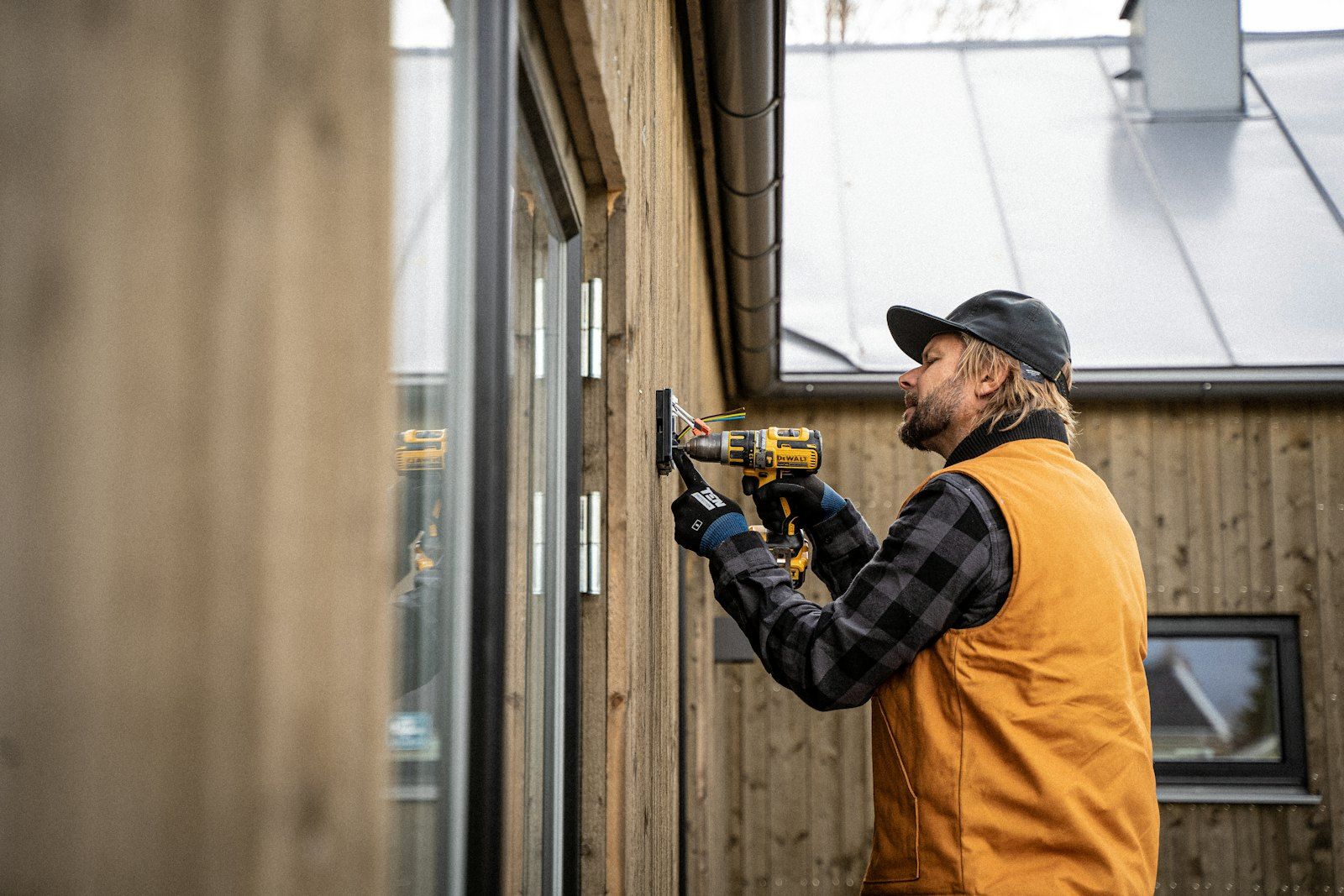 Artisan qui visse un bardage en bois