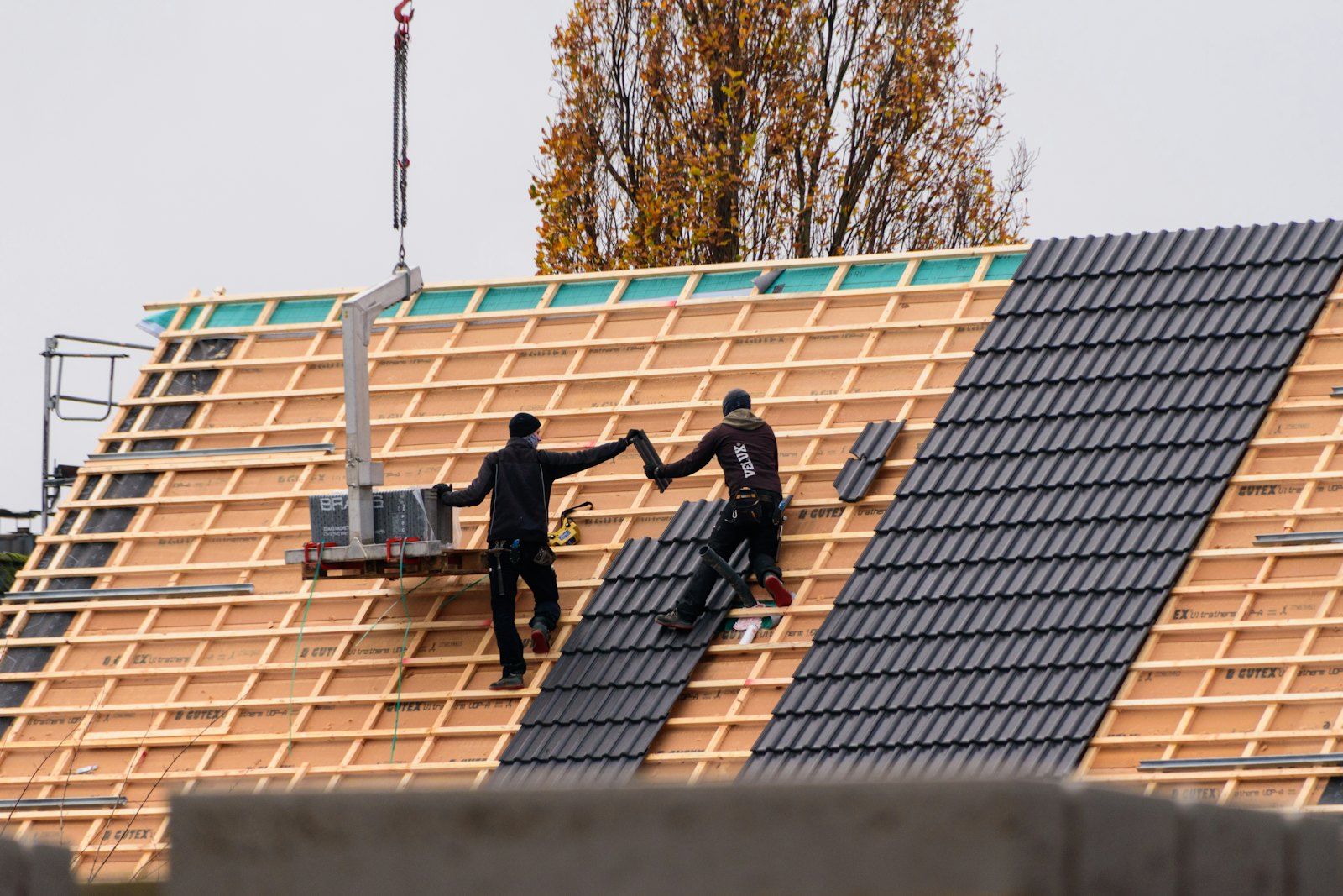 Couvreurs qui posent des tuiles sur un toit neuf